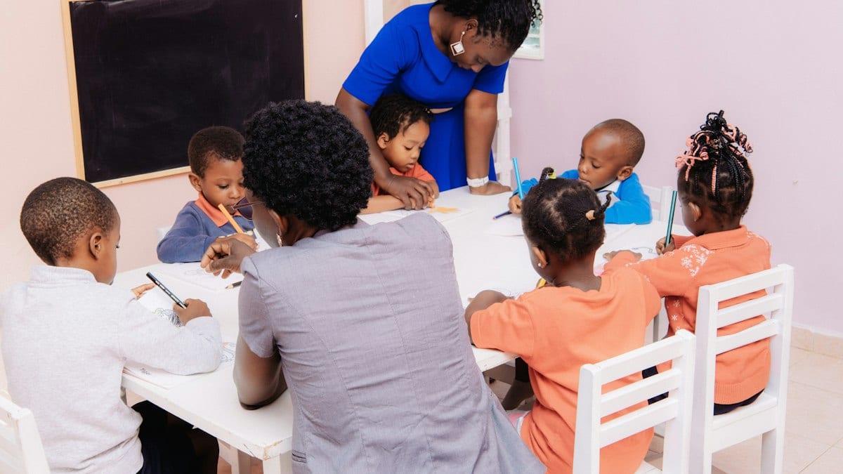 Enseignant guidant des enfants qui dessinent à une table