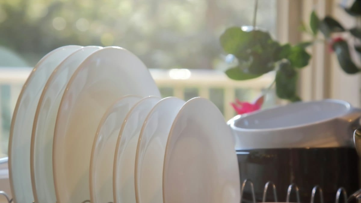 Lumière du soleil illuminant des assiettes et bols blancs dans un égouttoir