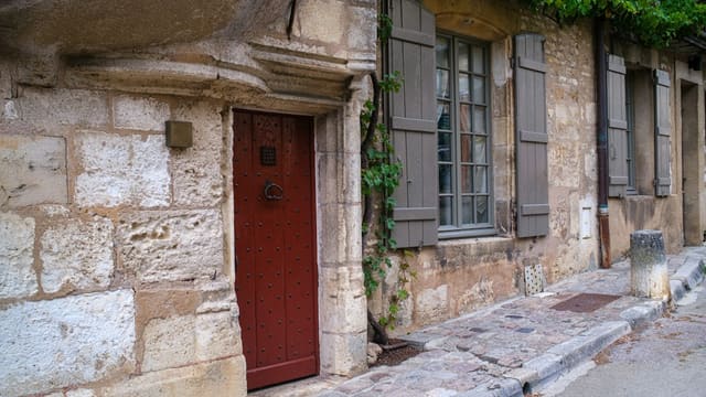 Old stone building with a red door and shutters