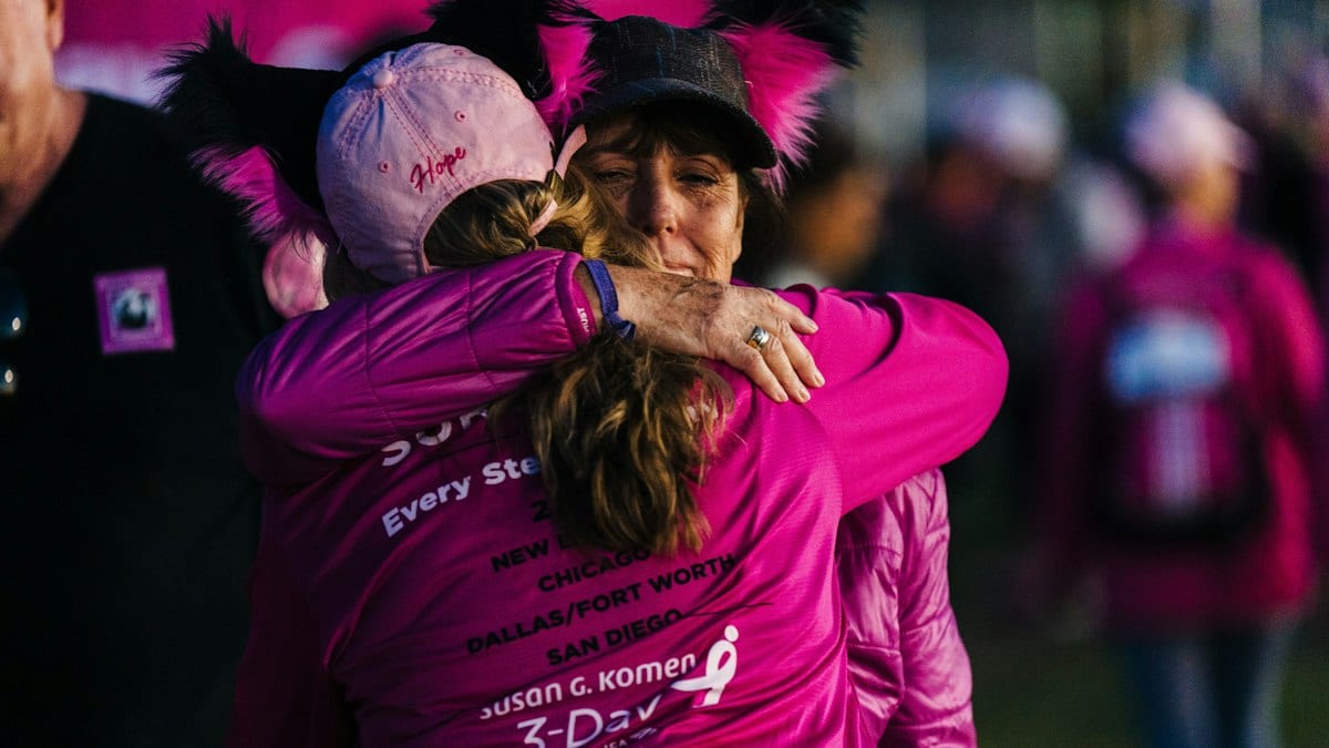 Deux marcheuses vêtues de rose s'étreignent lors d'une marche de sensibilisation au cancer du sein