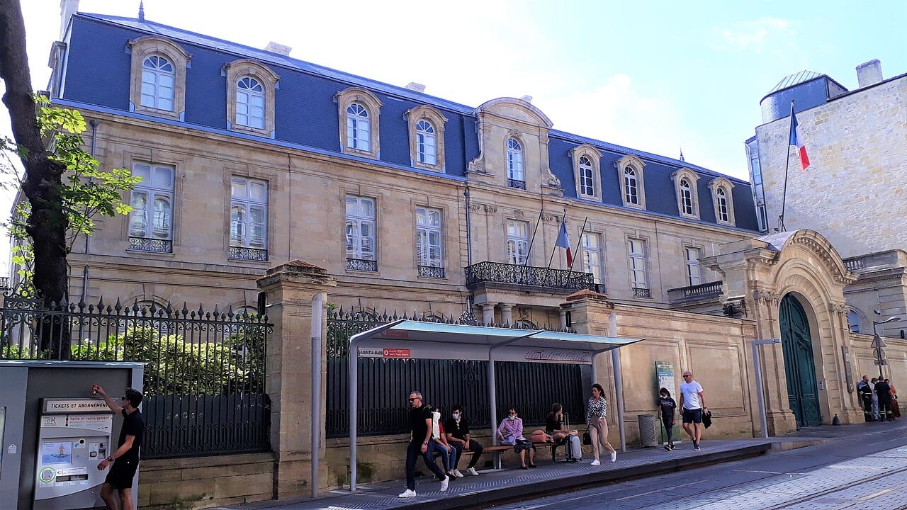 La façade de l'hôtel de Nesmond, résidence des préfets de la Gironde, photographiée en juillet 2021, avec ses drapeaux tricolores et un arrêt de tramway devant ses grilles.