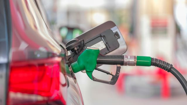Pistolet de pompe à essence inséré dans le réservoir d'une voiture à la station-service.