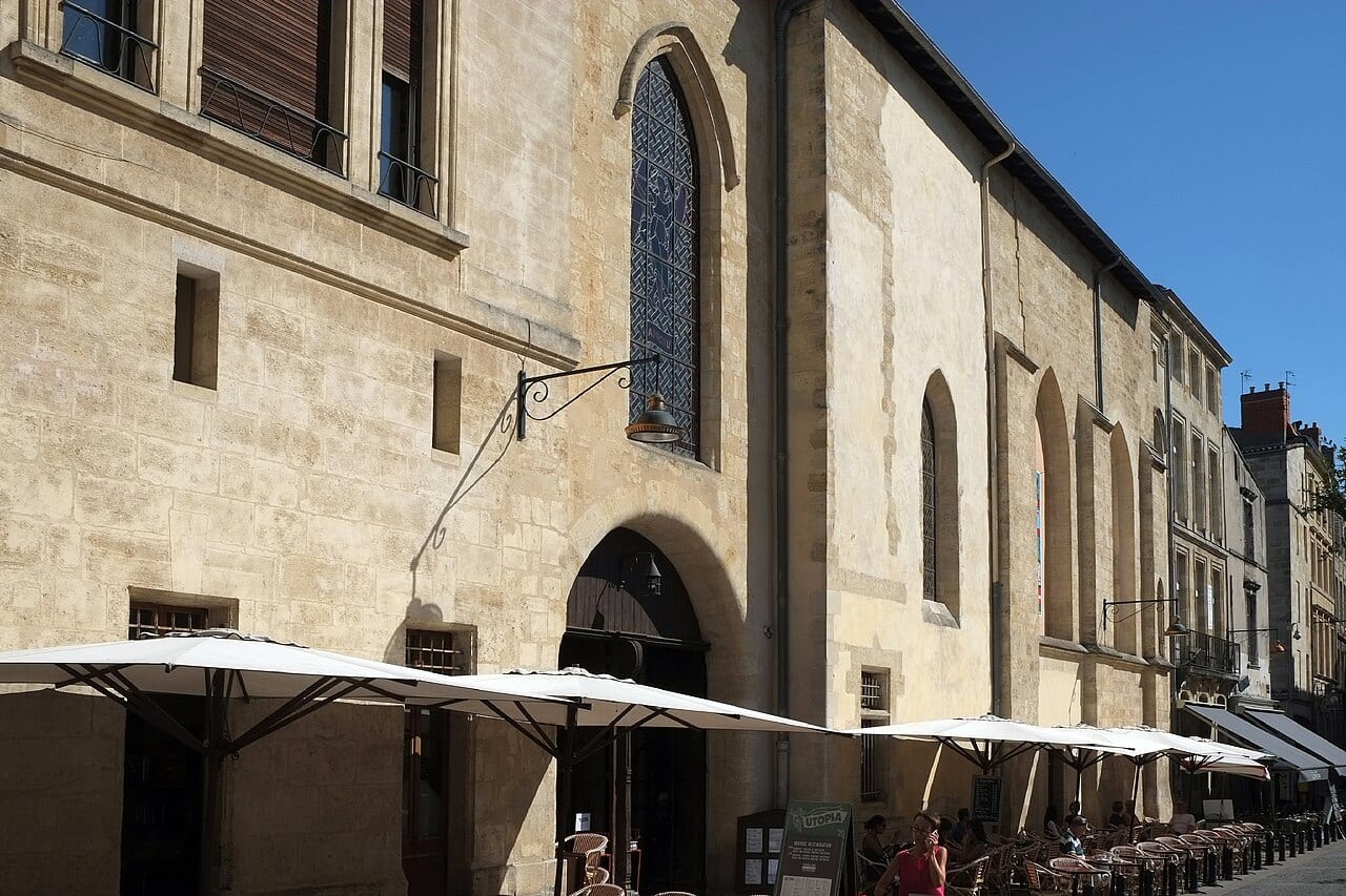 Façade en pierre du cinéma Utopia à Bordeaux, ancienne église, avec sa terrasse et ses parasols blancs.