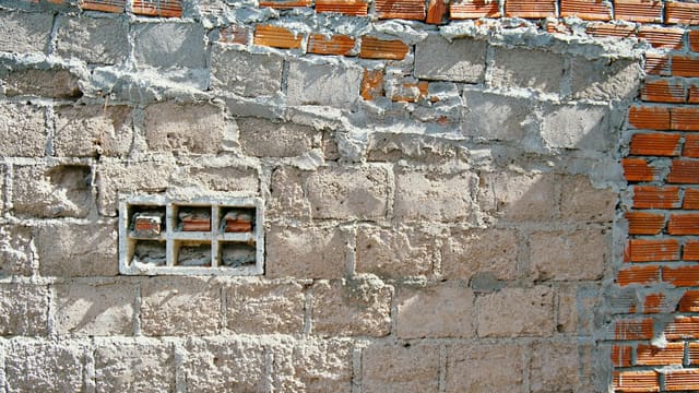 Rough brick wall with a small glass block window