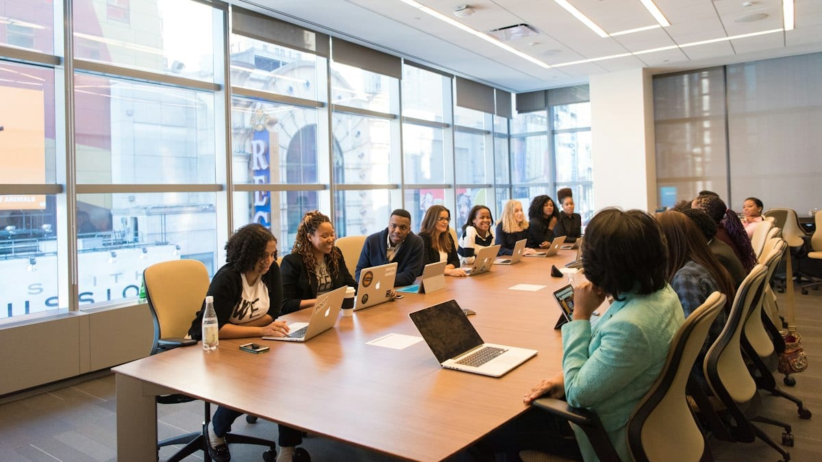 Groupe assis à une table en bois avec ordinateurs