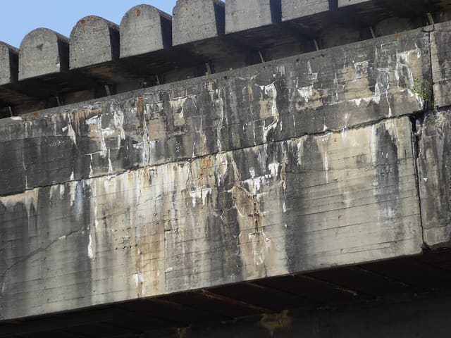Béton gris et usé de la Base sous-marine de Bordeaux, avec les créneaux arrondis du rebord de toit.