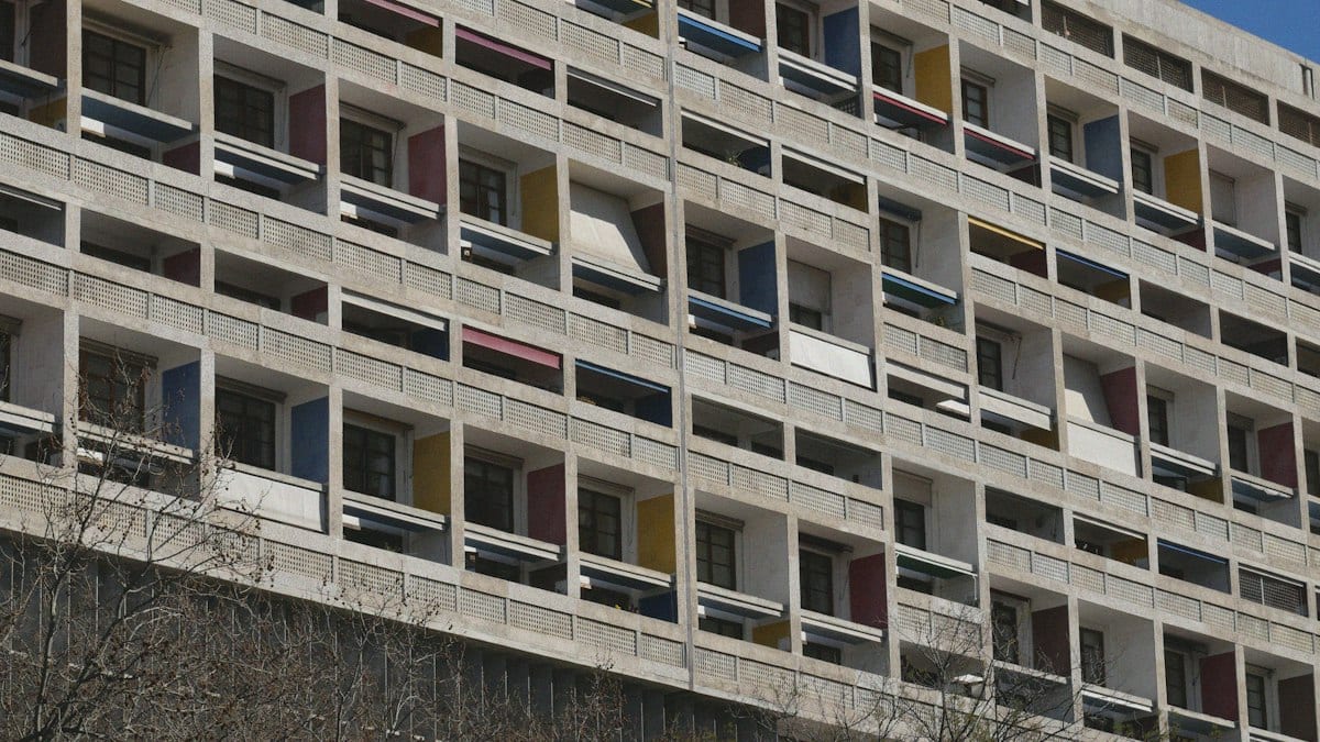 Façade d'un grand immeuble d'habitation en béton aux loggias colorées, vue en contre-plongée, image d'illustration du logement collectif