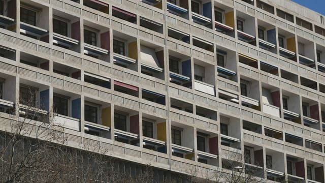 Façade d'un grand immeuble d'habitation en béton aux loggias colorées, vue en contre-plongée, image d'illustration du logement collectif