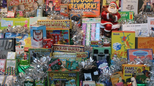 Piles de jouets et de jeux de société décorés de guirlandes argentées, avec un père Noël en figurine