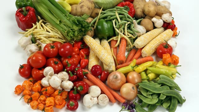 Un assortiment de légumes colorés, tomates, poivrons, maïs et carottes, préparés pour la cuisine.
