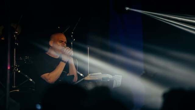 A man performing on stage with instruments and spotlights