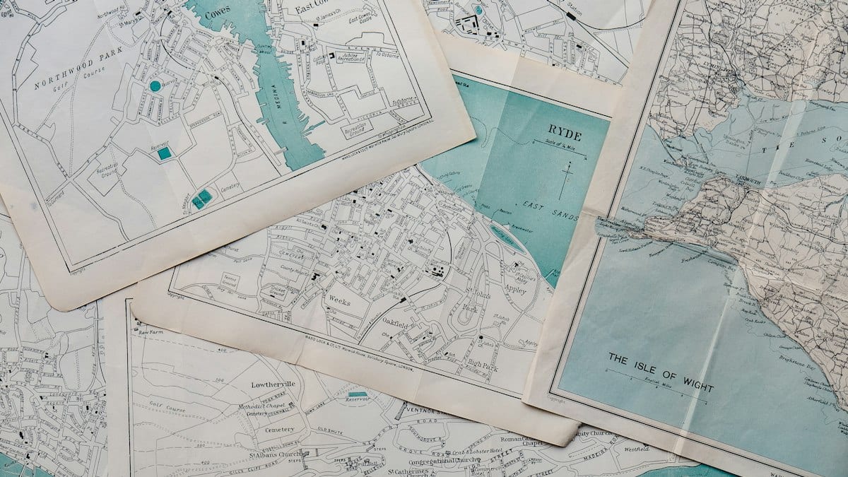 Plusieurs cartes anciennes de villes posées les unes sur les autres, illustrant la consultation sur le plan local d'urbanisme.
