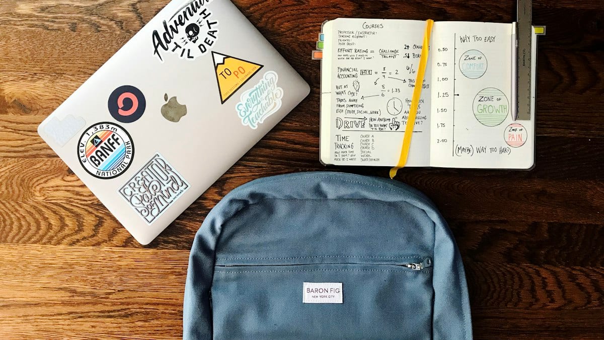 Sac à dos bleu, livre et MacBook argenté en mise en scène