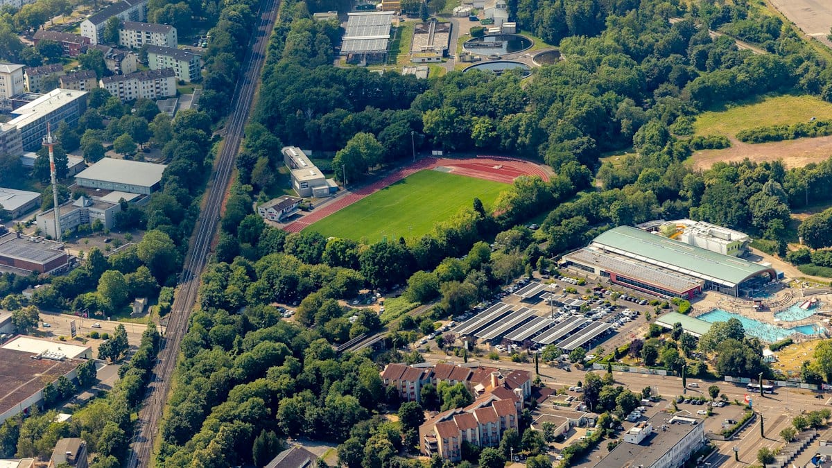 Aerial view of a sports field, railway, and urban landscape.