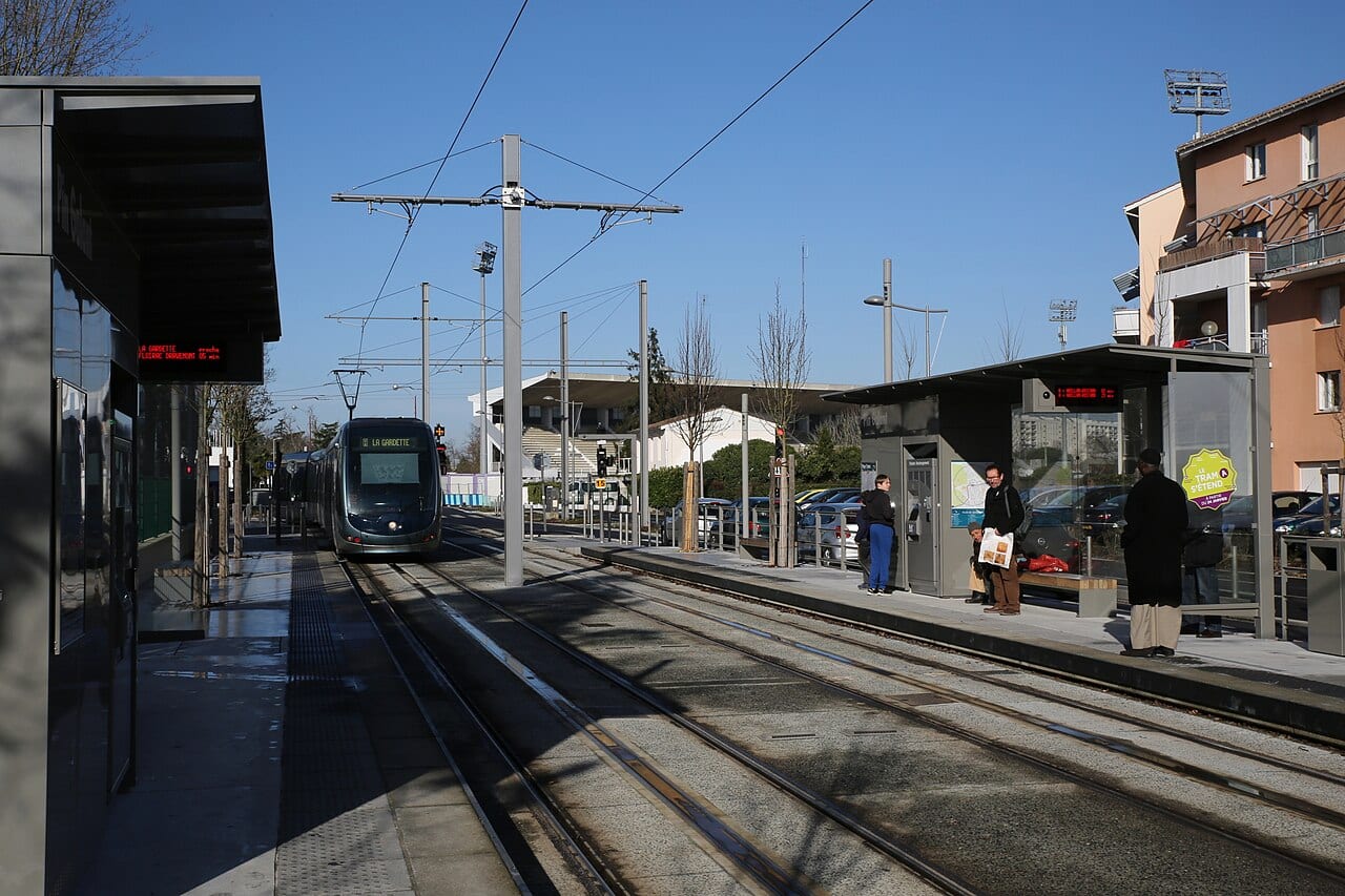 Une rame du tram A à quai, avec des voyageurs attendant sur le quai d'une station du réseau TBM.