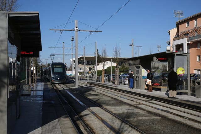 Une rame du tram A à quai, avec des voyageurs attendant sur le quai d'une station du réseau TBM.