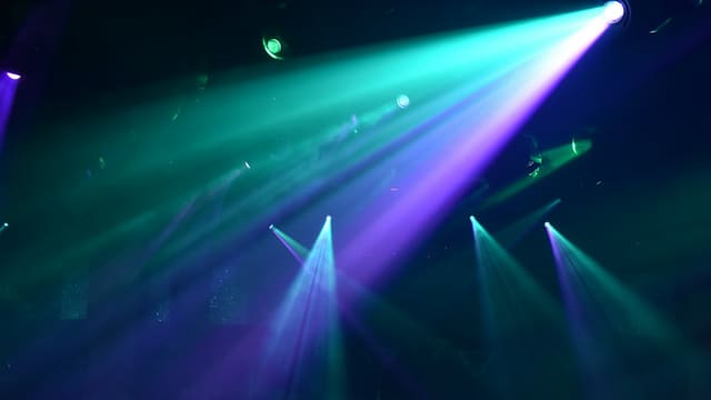 Jeux de lumières colorées sur une scène de concert dans l'obscurité.