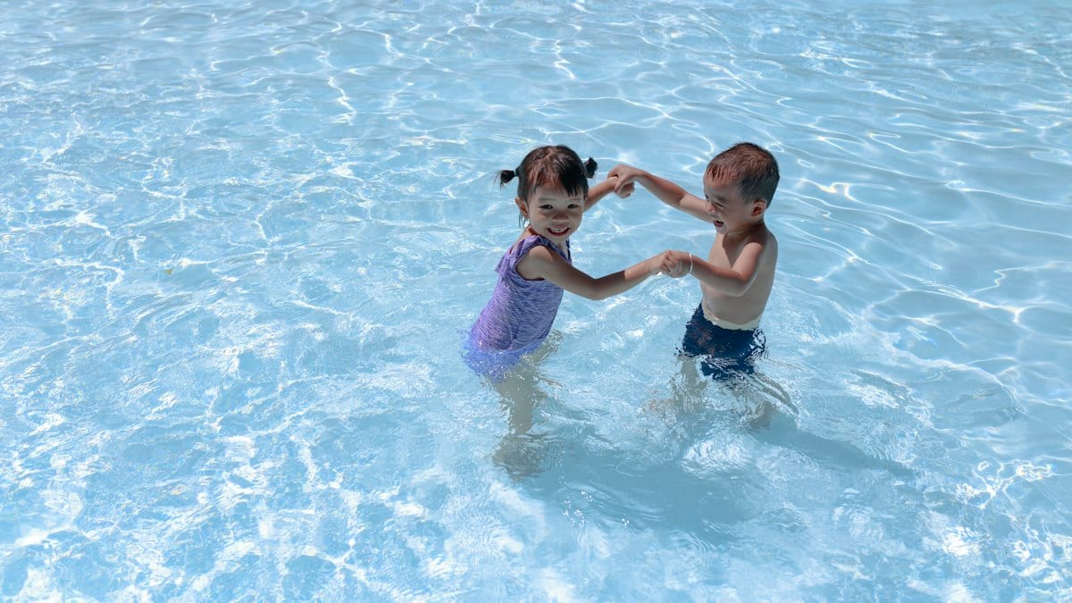 Deux enfants jouent dans l'eau d'une piscine, illustration des activités aquatiques proposées pendant les vacances