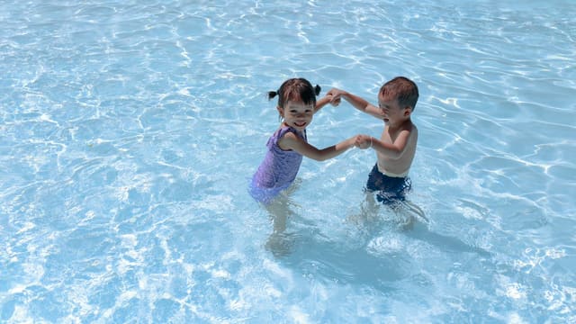 Deux enfants jouent dans l'eau d'une piscine, illustration des activités aquatiques proposées pendant les vacances