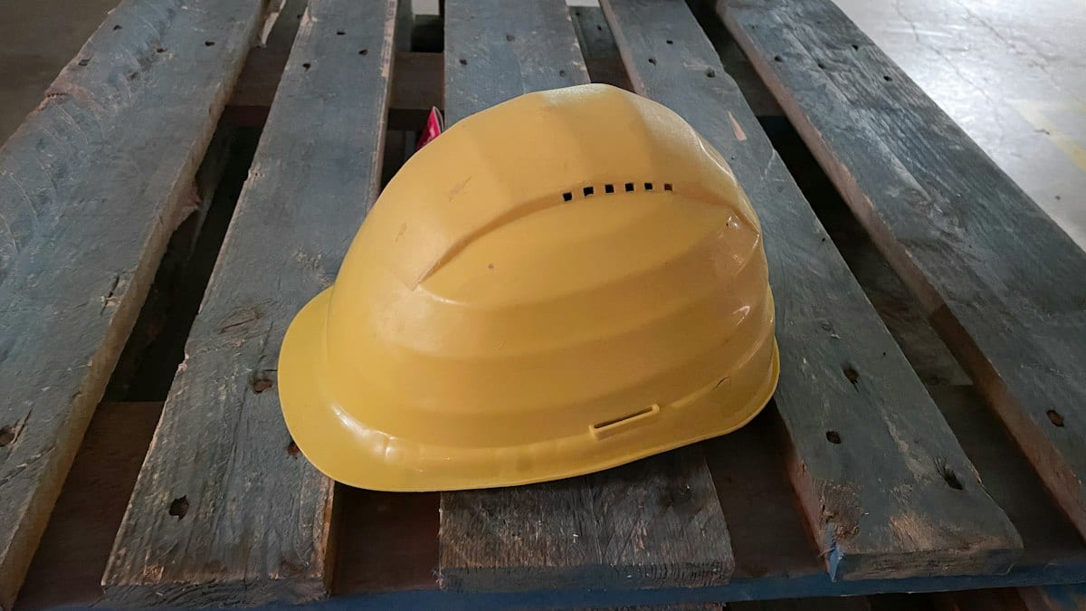 Casque de chantier jaune posé sur des palettes en bois