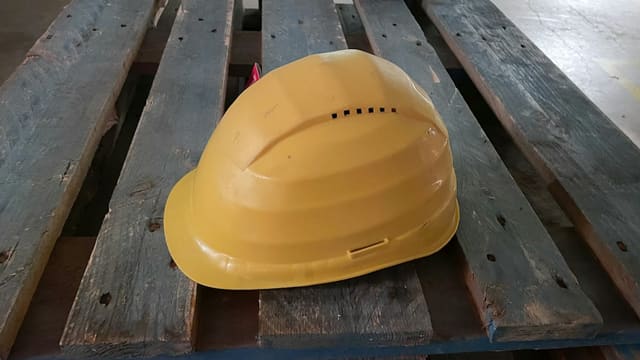 Casque de chantier jaune posé sur des palettes en bois
